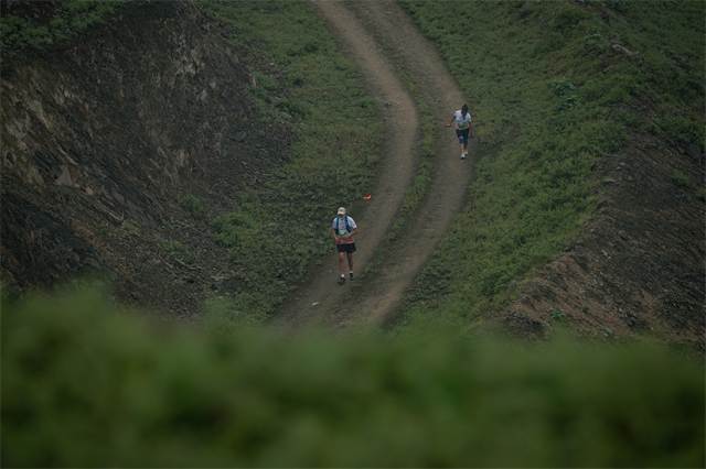 Corredor solitario sobre una trocha estrecha entre lomas verdes