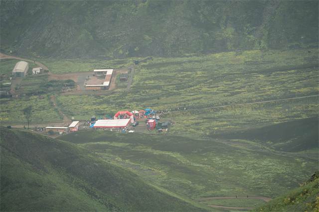 Campamento base visto desde lo alto del cerro, rodeado de lomas verdes