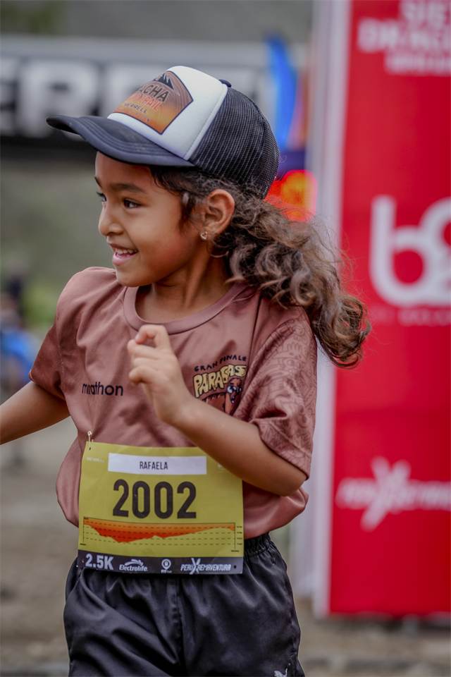Niña con gorra oficial corriendo hacia la meta del 3 K Kids