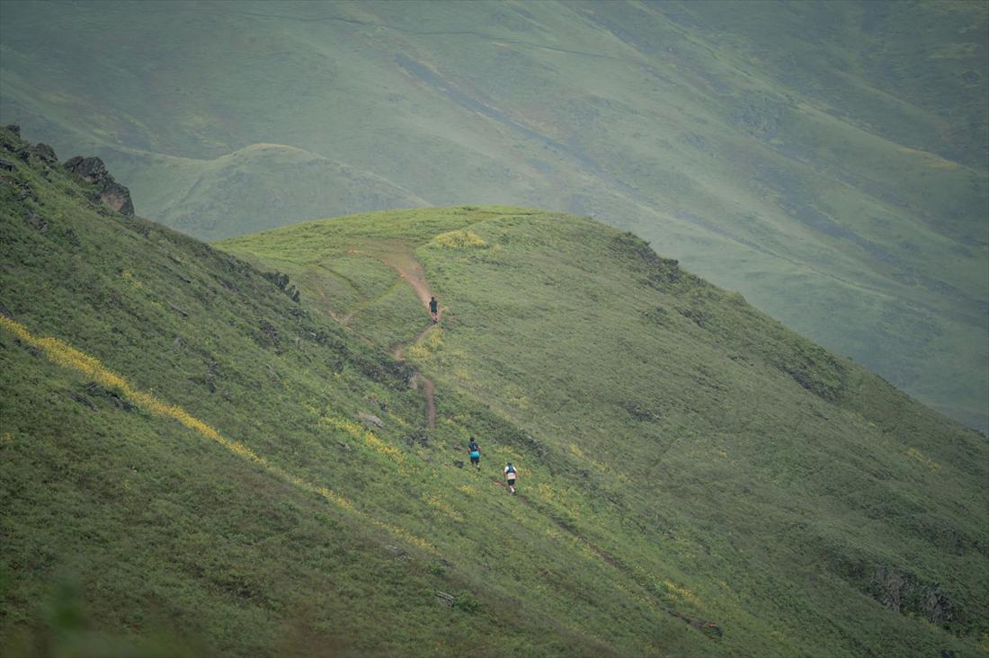 Dos corredores diminutos sobre una loma verde inmensa del Santuario, con el valle cubierto de garúa al fondo