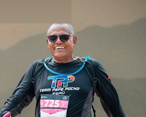 Corredor de cabello cano sonriendo mientras avanza por la trocha con bastones