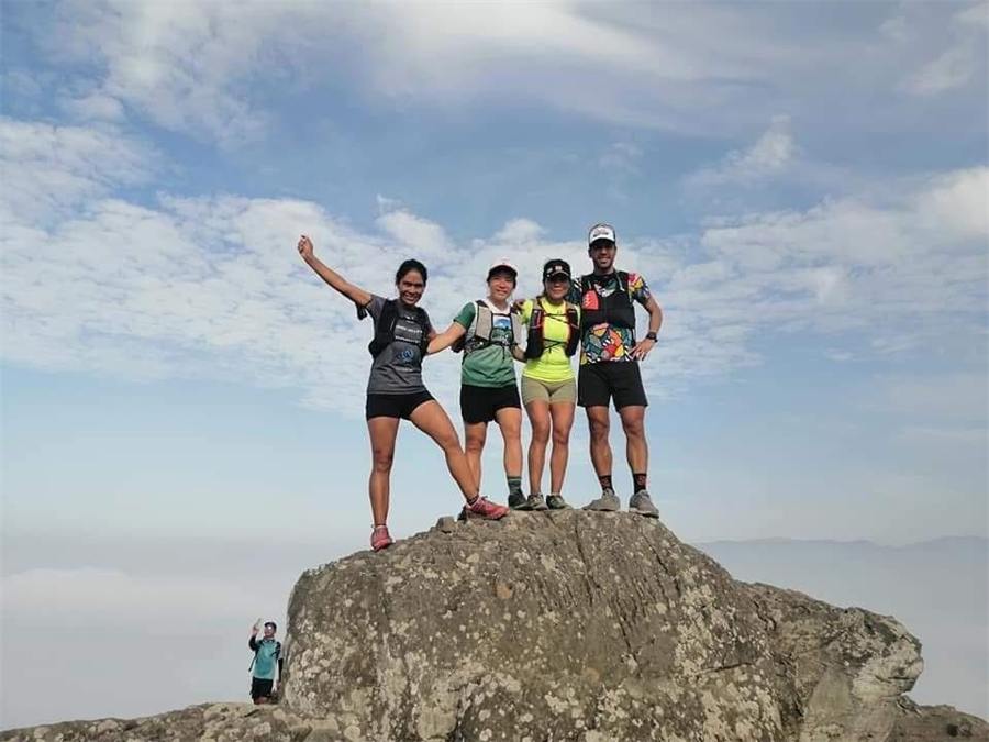 Corredores celebrando sobre una roca en la cima