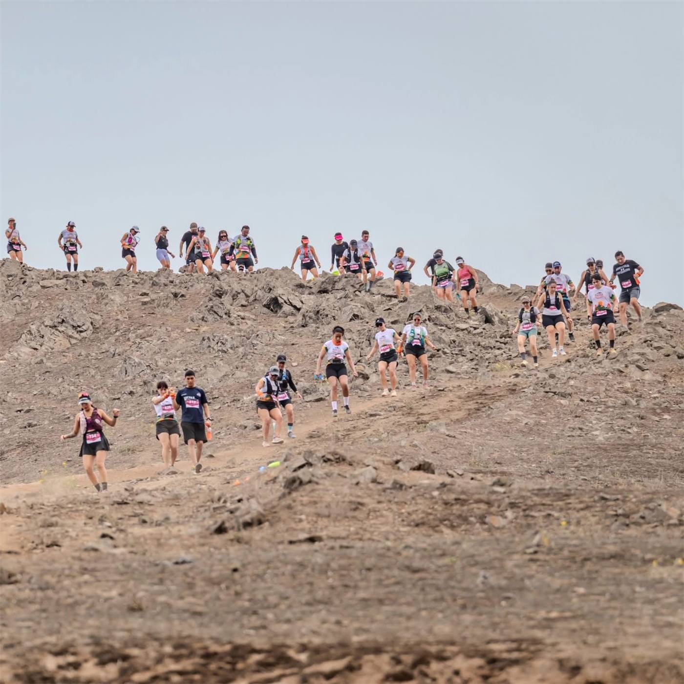 Corredores bajando una cresta seca y rocosa del Santuario de Amancay en temporada de verano