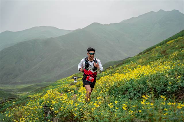 Corredor avanzando por una ladera cubierta de flores