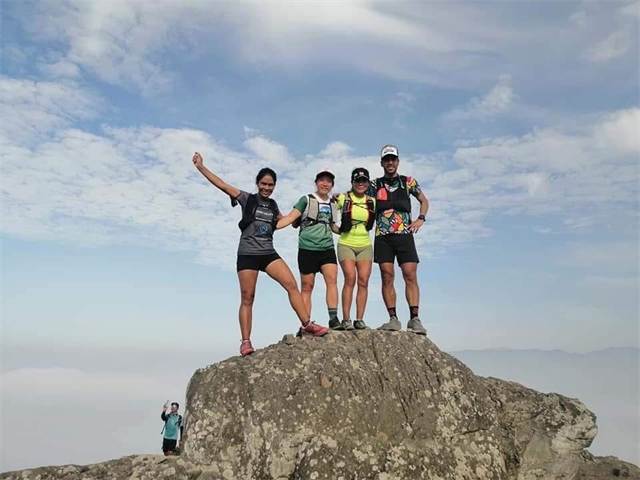 Corredores celebrando sobre una roca en la cima